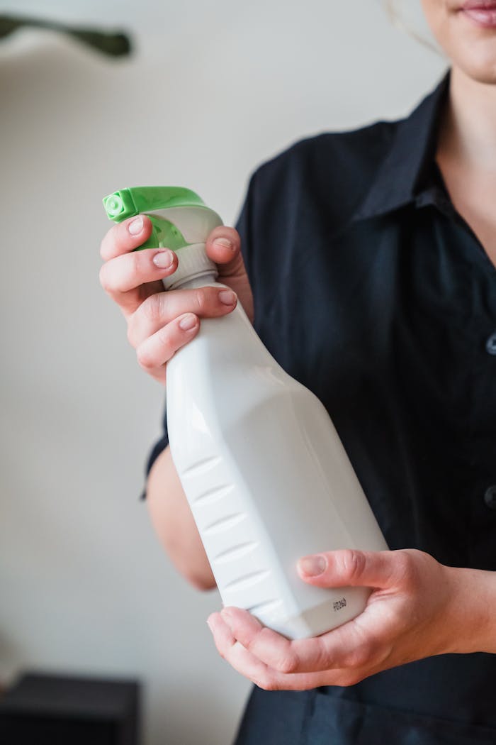 Mastering the First Impression: Your intriguing post title goes here Close-up of a person holding a white spray bottle with a green nozzle, indoors.